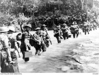 Huon Peninsula, New Guinea. 1943-12-13. AIF infantrymen wading across the Song River before attacking Japanese positions on the Huon Peninsula