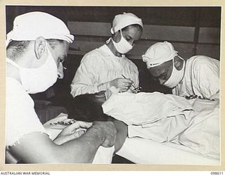 RABAUL, NEW BRITAIN. 1945-11-02. THE ANAESTHETIST (1); SISTER JONES, AUSTRALIAN ARMY NURSING SERVICE (2), AND MAJOR SCOTT (3) AT WORK DURING A MAJOR OPERATION AT 105 CASUALTY CLEARING STATION