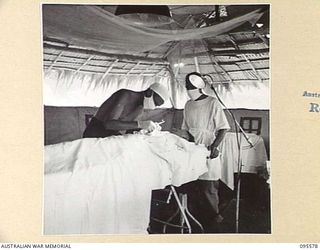 CAPE WOM, WEWAK AREA, NEW GUINEA. 1945-08-28. CAPTAIN J.C. ZWAR, MEDICAL OFFICER, 104 CASUALTY CLEARING STATION STITCHING THE FINGER OF SAPPER J.A. BOLYTH, ASSISTED BY PRIVATE A.F. HUMPHREYS, ..