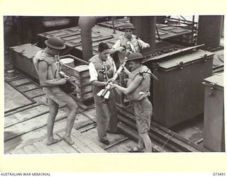 AT SEA, 1944-05-12. MEMBERS OF THE RAN HANDLING ROCKETS ABOARD THE TROOPSHIP ORMISTON. THE SHIP, HEADING FROM PORT MORESBY TO LAE, CARRIES 16 NAVAL PERSONNEL UNDER THE COMMAND OF WARRANT OFFICER A. ..