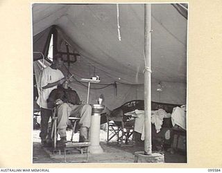 CAPE WOM, WEWAK AREA, NEW GUINEA. 1945-08-28. CAPTAIN K. JOHNSON, DENTIST, 104 CASUALTY CLEARING STATION, GIVING TREATMENT TO PRIVATE D.A. COLEMAN