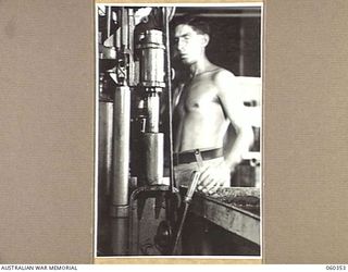 17 MILE, LALOKI RIVER, NEW GUINEA. 1943-11-22. QX44421 PRIVATE W. GRAY OPERATING A BOTTLING MACHINE AT THE CORDIAL FACTORY ESTABLISHED AND OPERATED BY THE HEADQUARTERS, NEW GUINEA FORCE AT SAPPHIRE