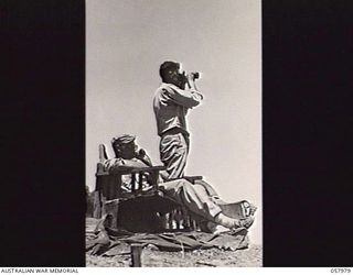 LAE, NEW GUINEA. 1943-10-11. GUNNERS, PRIVATE H. WHEELER (SEATED) AND CORPORAL D. DIBELLO OF "D" BATTERY, 102ND COAST ARTILLERY BATTALION, ANTI-AIRCRAFT (AW), UNITED STATES ARMY, ON THE LOOKOUT FOR ..