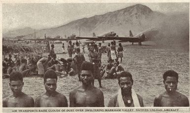 Air transports raise clouds of dust over sweltering Markham Valley. Natives unload aircraft