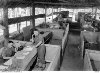 Lae, New Guinea. 1944-06-29. Major H. W. Gale, Camp Commandant (left front), and Captain C. F. Brady, Second in Command, seen in a section of the Orderly room at HQ, New Guinea Force