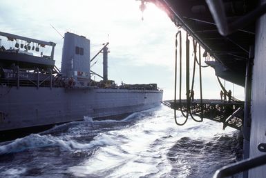 Crew members aboard the amphibious assault ship USS GUAM (LPH-9) pass lines between their vessel and the tank landing ship USS LA MOURE COUNTY (LST-1194) as the two ships prepare to conduct underway replenishment operation