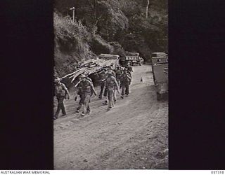 Troops of the 2/12th Battalion passing vehicles held up at the Rouna Traffic Control Post No. 2 because of blasting further along the road