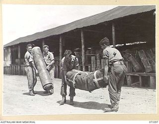 NADZAB, NEW GUINEA. 1944-05-25. MEMBERS OF THE 3RD AIR MAINTENANCE COMPANY CARRYING SUPPLY DROPPING CONTAINERS DURING PREPARATIONS FOR A PARACHUTE DROP TO TROOPS IN FORWARD AREA. THEY HOLD AN ..