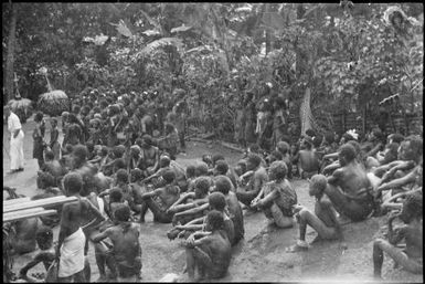 Large group of seated and standing people with two Dukduks at Rabaul Harbour, New Guinea, ca. 1929 / Sarah Chinnery