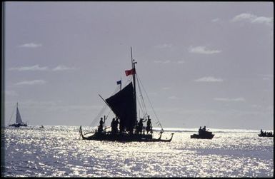 Silhouette of boat with triangle sail with people aboard