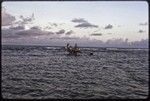 Manus: canoe approaches the beach at Pere, waves break on coral reef in background