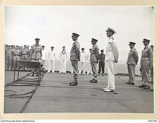AT SEA OFF RABAUL, NEW BRITAIN. 1945-09-06. AUSTRALIAN, ROYAL NAVY AND NEW ZEALAND OFFICERS LINED UP ON THE FLIGHT DECK OF THE AIRCRAFT CARRIER HMS GLORY, WAITING FOR THE ARRIVAL OF GENERAL H. ..