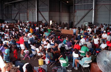 Evacuees from bases in the Philippines congregate in a hangar as they wait for the planes which will take them on the final stage of their journey to the United States. Civilian and military personnel and their dependents have been evacuated from Naval Station, Subic Bay and Naval Air Station, Cubi Point as part of Operation Fiery Vigil in the aftermath of Mount Pinatubo's eruption on June 10th.