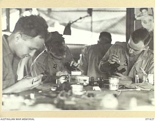 LAE, NEW GUINEA. 1944-03-24. INSTRUMENT MECHANICS REPAIRING BINOCULARS IN THE MOBILE WORKSHOP AT THE 2/125TH BRIGADE WORKSHOP ATTACHED TO THE 7TH DIVISION. IDENTIFIED PERSONNEL ARE: NX115620 ..