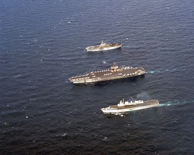 A port beam view of, from top to bottom, the amphibious assault ship USS GUAM (LPH-9), the aircraft carrier USS JOHN F. KENNEDY (CV-67) and the British aircraft carrier HMS ARK ROYAL (R-07) underway