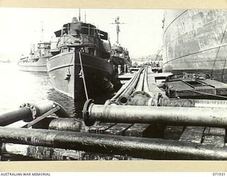 MILNE BAY, PAPUA, NEW GUINEA. 1944-04-03. AN OIL TANKER ON THE RIGHT DISCHARGES A CARGO OF PETROL BY PIPELINE TO 2ND BULK PETROLEUM STORAGE COMPANY. TO THE LEFT, UNITED STATES PATROL VESSELS ..