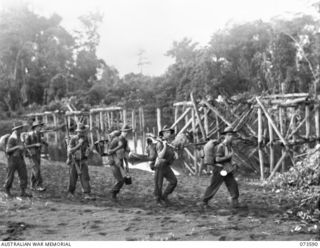 KARIM RIVER, NEW GUINEA. 1944-05-26. TROOPS OF THE 35TH INFANTRY BATTALION MOVE ALONG THE BEACH NEAR THE REMAINS OF A DEMOLISHED JAPANESE BRIDGE. THE UNIT IS ADVANCING UP THE COAST TOWARDS WEWAK. ..