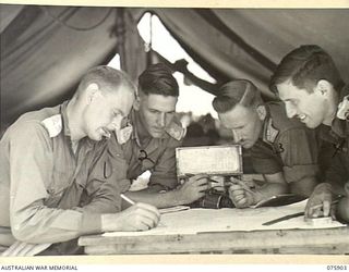 HANSA BAY AREA, NEW GUINEA. 1944-09-05. NX56558 LIEUTENANT H. SHEPHERD, 25TH INFANTRY BATTALION (1) PLANNING A 7 DAY JUNGLE PATROL FROM BOIKULU INTO THE RAMU RIVER AREA ASSISTED BY HIS FELLOW ..