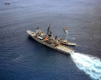 A harbor tug positions the salvage and rescue ship USS BRUNSWICK (ATS 3)