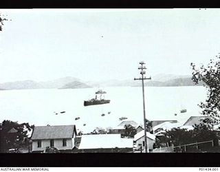 PORT MORESBY, NEW GUINEA. 1914-07. VIEW OF THE HARBOUR FROM A STREET IN THE TOWN, SHOWING THE CRUISER HMAS ENCOUNTER AND THE BURNS PHILP VESSEL MATUNGA AT ANCHOR. (ORIGINAL PRINT HELD IN AWM ..
