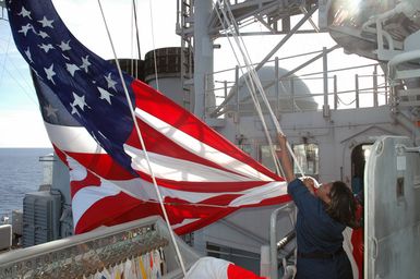 Onboard the US Navy (USN) Ticonderoga Class Guided Missile Cruiser (Aegis) USS COWPENS (CG 63), Quartermaster Second Class (QM2) Tamika Shead raises the National ENSIGN, while the ship is underway in the Pacific Ocean, during the opening phases of a joint US-Russian Naval Exercise. A Russian Federation Navy vessel made the first visit to the US Territory of Guam in order to participate in a joint humanitarian assistance and disaster relief exercise