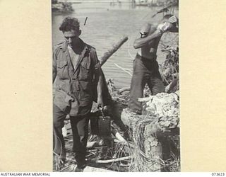 MARUKINAM RIVER, NEW GUINEA. 1944-05-28. S114004 PRIVATE G. HEIDRICH, 35TH INFANTRY BATTALION (1), CARRIES "BILLIES" FROM THE RIVER CONTAINING WATER. TOWARDS THE BACKGROUND PRIVATE R.W.A. BAKER ..