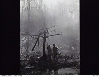 LAE, NEW GUINEA. EXTENSIVE DAMAGE CAUSED BY THE ALLIED AERIAL BOMBARDMENT. A COMBAT PHOTOGRAPHY UNIT IS AT WORK IN THE SMOKING RUINS. (NAVAL HISTORICAL COLLECTION)