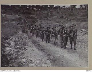 CAPE WOM, WEWAK AREA, NEW GUINEA. 1945-05-06. MEN OF 16 PLATOON, D COMPANY, 2/11 INFANTRY BATTALION, MARCH IN BATTLE ORDER DOWN THE MAIN ROAD TO THE COAST TOWARDS WEWAK DURING THEIR ADVANCE AGAINST ..