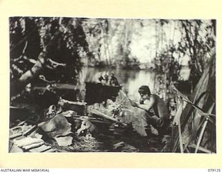 TSIMBA AREA, BOUGAINVILLE ISLAND. 1945-02-13. NX179419 PRIVATE J.T. PORTER, 31/51ST INFANTRY BATTALION HAVING A SHAVE AT HIS TEMPORARY CAMP ON THE BANKS OF THE GENGA RIVER