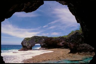 View of beach through rocky archway, Niue