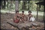 Mogiovyeka (r) and other men converse in a small group, Mogiovyeka smokes a cigarette