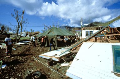 A tent is erected amid the houses and debris, destroyed by Cyclone Val on American Samoa, by members of the 100th Battalion, 42nd Infantry Division, American Samoa. Exact Date Shot Unknown