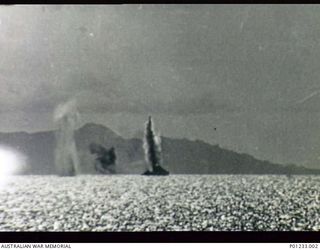 GUADALCANAL, SOLOMON ISLANDS, 1942-08-07. OFF TULAGI, JAPANESE AIRCRAFT DIVE BOMB THE DESTROYER USS MUGFORD. SHE WAS HIT IN THE STERN BY A MEDIUM BOMB KILLING TWENTY-ONE CREW. THIS PHOTOGRAPH WAS ..