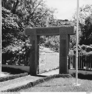 ELA BEACH, PORT MORESBY, 1954-08. THE MEMORIAL GATEWAY TO THE MEMORIAL CEMETERY AT ELA BEACH. THE GATEPOSTS ARE ENSCRIBED WITH THE NAMES OF ALL THE RESIDENTS OF PAPUA WHO ENLISTED FOR ACTIVE ..