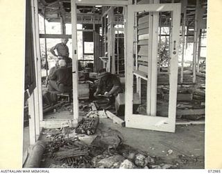 MADANG, NEW GUINEA. 1944-04-24. TROOPS OF THE 5TH DIVISION EXAMINE ENEMY EQUIPMENT ABANDONED BY JAPANESE FORCES WHO HAD OCCUPIED THE HOUSE ON THE PREVIOUS DAY