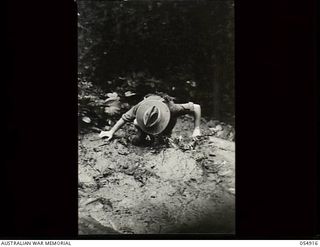 Bulldog-Wau Road, New Guinea. 1943-07-14. An Australian soldier making a precipitous climb up a slippery side track. At this time the road between the twenty one and a half and twenty three mile ..