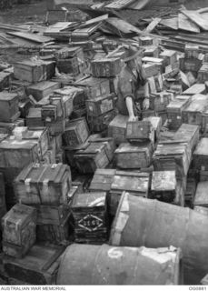 KIRIWINA, TROBRIAND ISLANDS, PAPUA. 1943-11-27. LEADING AIRCRAFTMAN T. BASTIN OF RICHMOND, VIC, STACKING AMMUNITION BOXES FOLLOWING THE MOVE OF NOS. 22 AND 30 SQUADRONS RAAF FROM GOODENOUGH TO ..