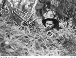 DAGUA, NEW GUINEA. 1945-03-27. PTE L.H. TUCKEY, NO.8 PLATOON, A COMPANY, 2/2 INFANTRY BATTALION, MANNING A .303 BREN LIGHT MACHINE GUN BESIDE THE TRACK TO GUARD THE LINE OF COMMUNICATION BETWEEN ..