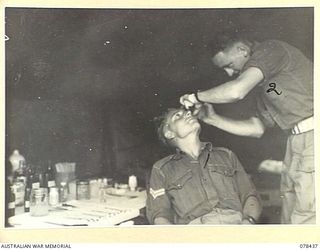 MOTUPINA POINT AREA, BOUGAINVILLE ISLAND. 1945-01-19. 20. VX87040 SERGEANT WALLACE, REGIMENTAL AID POST SERGEANT (2) TREATING VX109384 CORPORAL W.H. EADE (1) AT THE REGIMENTAL AID POST OF NO.5 ..