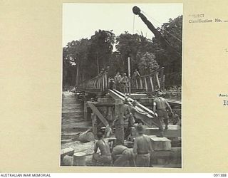 BOUGAINVILLE. 1945-05-01. SAPPERS OF 15 FIELD COMPANY, ROYAL AUSTRALIAN ENGINEERS, AND A MOBILE CRANE FITTING A GIRDER INTO POSITION AT THE APPROACHES TO THE NEW AUSTPANEL BRIDGE ACROSS THE PURIATA ..