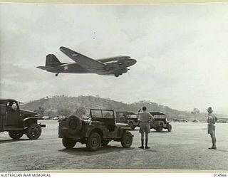 1943-06-09. NEW GUINEA. PORT MORESBY. TRAFFIC IS HELD UP AT THE END OF THE AIR STRIP WHILE A TRANSPORT PLANE TAKES OFF. (NEGATIVE BY N. BROWN)