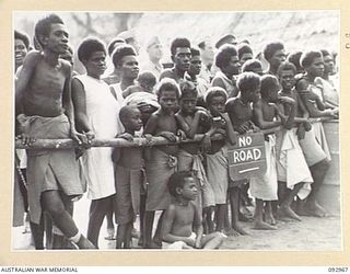 TOROKINA, BOUGAINVILLE. 1945-06-10. NATIVE WIVES AND PICCANINNIES WATCHING THE NATIVE SING-SING AT THE WEBB ROAD COMPOUND ON THE NUMA NUMA TRAIL WHICH WAS ATTENDED BY A LARGE NUMBER OF TROOPS. THE ..