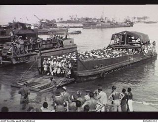 BOUGAINVILLE, 1945-09. JAPANESE POWs FROM NAURU, BUIN, KIETA, BUKA ISLAND AND OTHER PARTS OF BOUGAINVILLE ON A LANDING CRAFT IN THE PURIATA RIVER. THEY ARE BEING LANDED TO BEGIN THE MARCH TO POW ..