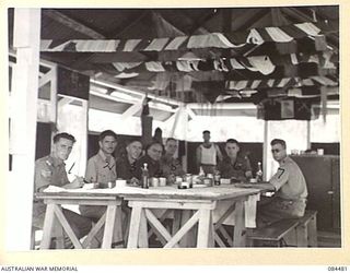 LAE, NEW GUINEA. 1944-12-18. SERGEANTS SEATED AT LUNCH IN THE SERGEANTS' MESS, 12 SMALL SHIP COY