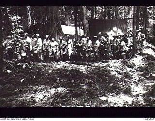 DREGER HARBOUR, NEW GUINEA. 1943-11-02. TROOPS OF "A" COMPANY, 808TH UNITED STATES ENGINEER AVIATION BATTALION AT THEIR MESS PARADE IN MUD AND SLIME DURING THE CONSTRUCTION OF A NEW AIRSTRIP. ..