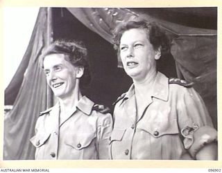 RABAUL AREA, NEW BRITAIN. 1945-09-17. SISTER M.M. WILSON (1) AND SISTER F.E. HENRY (2), STANDING IN FRONT OF THEIR TENT INSIDE A SPECIAL AREA AT 4 FIELD AMBULANCE. THE NURSING SISTERS WERE FLOWN TO ..