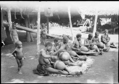 Seven women seated on mats while working on pots, Madang, New Guinea, ca. 1935 / Sarah Chinnery