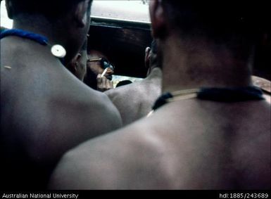 Man smoking in vehicle, surrounded by others