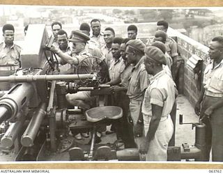 SYDNEY, NSW. 1944-01-26. NX71127 LIEUTENANT F. O. CRAGO, OFFICER COMMANDING, 655TH LIGHT ANTI-AIRCRAFT BATTERY EXPLAINING A BOFORS 40MM ANTI AIRCRAFT GUN TO AUSTRALIAN AND NEW GUINEA ADMINISTRATION ..