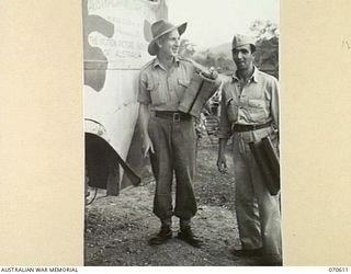 PORT MORESBY, PAPUA, 1944-02-25. AN AUSTRALIAN SOLDIER AND AN AMERICAN SERVICEMAN ARRIVING WITH PORTABLE SEATS AT A FIELD CINEMA. THE PICTURES ARE SHOWN AT HEADQUARTERS, NEW GUINEA FORCE BY THE ..